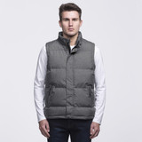 A grey puffa vest with a high collar and buttons, featuring two side pockets and a logo. Model is wearing a white long-sleeve shirt. A grey puffa vest with a high collar and buttons, featuring two side pockets and a logo. Model is wearing a white long-sleeve shirt.