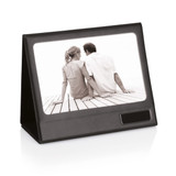 A black photo frame displaying a monochrome image of a couple seated together. The frame has a logo on it.