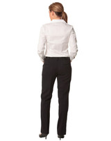 A woman stands facing away, wearing black low rise pants made from wool stretch, paired with a white shirt.