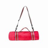 A red picnic blanket rolled up with a striped carrying strap, featuring black clips and a handle for easy transport. A red picnic blanket rolled up with a striped carrying strap, featuring black clips and a handle for easy transport.