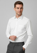 A white long sleeve button-up shirt with a chest pocket, modelled by a man in grey trousers.