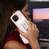 A pink magnetic power bank with a phone stand, held by a person near a computer screen. The product has a logo on it. A pink magnetic power bank with a phone stand, held by a person near a computer screen. The product has a logo on it.