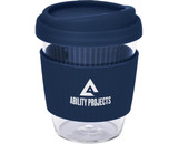 A reusable coffee cup in clear glass with a navy blue silicone lid and band, featuring a logo.