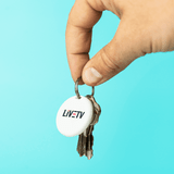 A hand holding a set of keys attached to a round white item tracker with a logo.