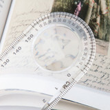 A transparent magnifying ruler measuring 15cm, featuring a circular magnifier and measurement markings.