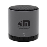 A grey Bluetooth speaker with a rounded design and a logo on the front. Features control buttons at the base.