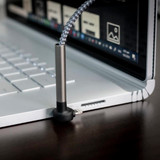 A charging cable with a braided design, featuring a metallic connector, plugged into a laptop.