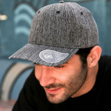 A grey cap with a mid visor and a logo on the brim, featuring a textured fabric design.