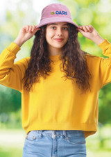 A purple terry towelling bucket hat worn by a woman with curly hair, paired with a yellow sweater and blue jeans.