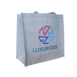 A beige jute tote bag with a logo and the word “LUXURIOUS” in blue and pink.