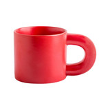 A red ceramic coffee mug with a unique handle design and a glossy finish. The mug features a logo.