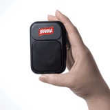 A hand holding a small black speaker with a mesh front and a logo on top.