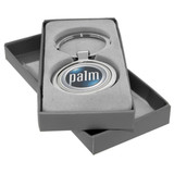 A keychain with a circular metallic design, presented in a grey box with soft padding.