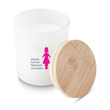 A medium white candle with a bamboo lid, featuring a logo on the front in pink.