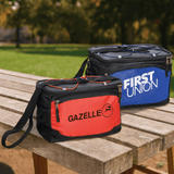 Two cooler bags in red and blue, each with a zipper and a shoulder strap, placed on a wooden table outdoors.