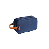A navy toiletry bag with a brown leather handle and two zippered compartments. Features a branding logo.