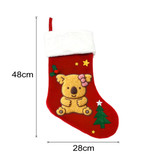 A red Christmas stocking featuring a koala design, fluffy white cuff, and decorated with stars and a green tree.