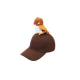 A brown baseball cap with a plush bird decoration perched on top. The cap features a logo.