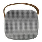 A compact speaker with a square design and mesh front, featuring a brown carrying strap.