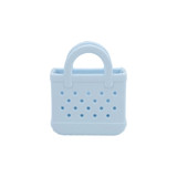A light blue mini EVA bag charm with perforated design and two handles, featuring a logo.