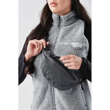 A grey Teton waist pack is being held by a person wearing a textured grey vest. The pack features a zippered compartment and branding.