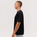 A black Core Tee displayed on a model, showcasing its side profile against a plain background.