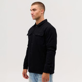 A black Studio Canvas Jacket is displayed on a model, showcasing its button-up design and front pockets.