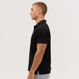 A black polo shirt displayed on a model from the side, featuring a subtle logo on the chest.