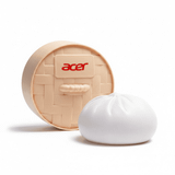 A squishy bun-shaped stress toy in white with a beige woven basket container, featuring a logo on the front.