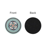 A round trivet featuring a decorative floral design in pastel colours on one side and a black textured surface on the reverse.
