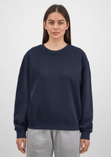 A navy crew sweatshirt for women featuring a relaxed fit, paired with grey sweatpants. It has a logo on the front.