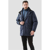 A man models a dark blue Men's Fairbanks 5-in-1 System Jacket with multiple pockets and a detachable inner layer.
