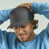 A grey trucker cap with a mesh back, worn by a smiling man in a light blue sweatshirt.