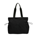 A lightweight black tote bag with yoga mat straps and two front pockets. It has long handles for easy carrying.