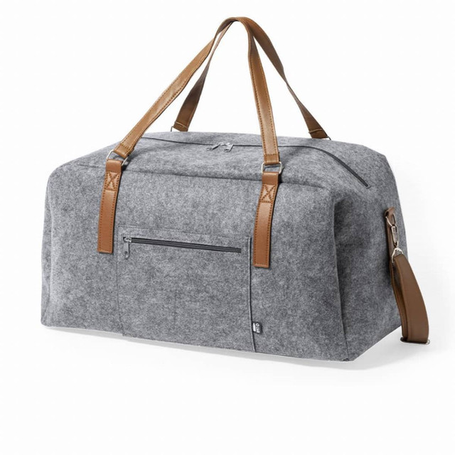 A grey felt duffel bag with brown leather straps, featuring a front zip pocket and a detachable shoulder strap. A grey felt duffel bag with brown leather straps, featuring a front zip pocket and a detachable shoulder strap.