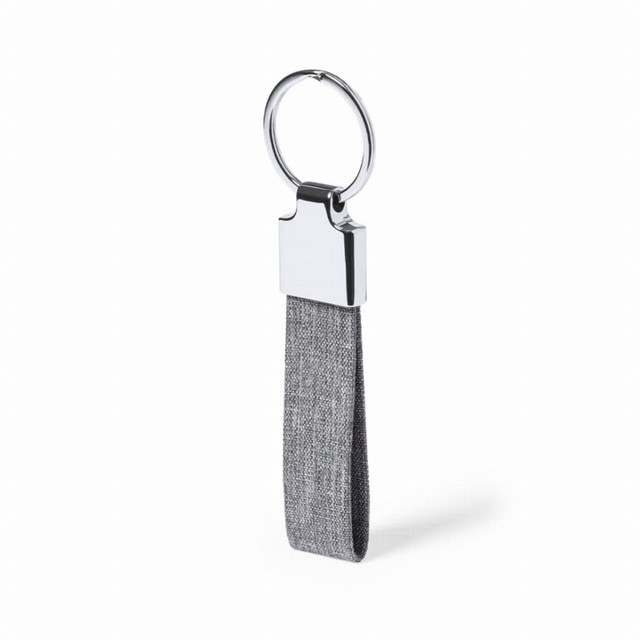 A keychain featuring a grey fabric strap and a shiny chrome metal attachment. It includes a logo on the metal part. A keychain featuring a grey fabric strap and a shiny chrome metal attachment. It includes a logo on the metal part.