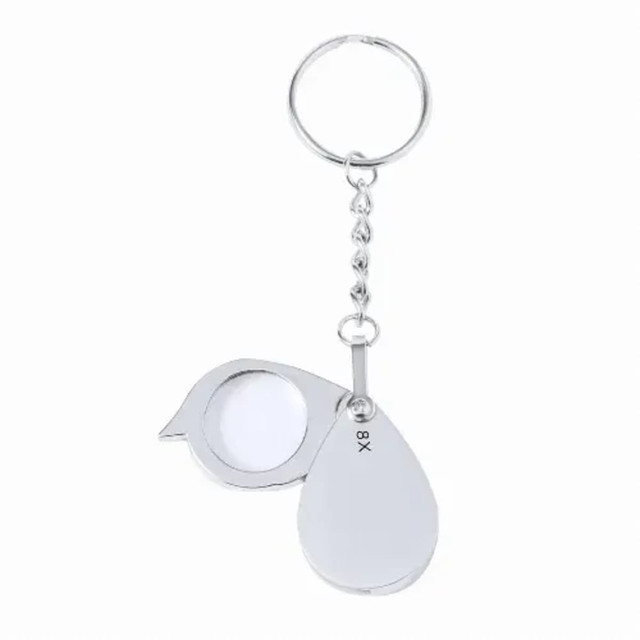 A silver magnifier keyring with an 8X magnification lens and a teardrop shape. Includes a circular keyring attachment. A silver magnifier keyring with an 8X magnification lens and a teardrop shape. Includes a circular keyring attachment.