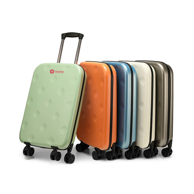 A set of collapsible suitcases in green, orange, blue, cream, and grey, featuring wheels and a handle. Each suitcase has a logo. A set of collapsible suitcases in green, orange, blue, cream, and grey, featuring wheels and a handle. Each suitcase has a logo.