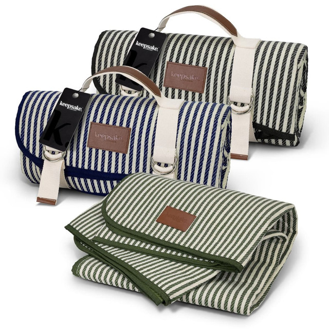 A striped picnic blanket in navy blue and green, featuring leather accents and a logo. One blanket is rolled, the other unfolded. A striped picnic blanket in navy blue and green, featuring leather accents and a logo. One blanket is rolled, the other unfolded.