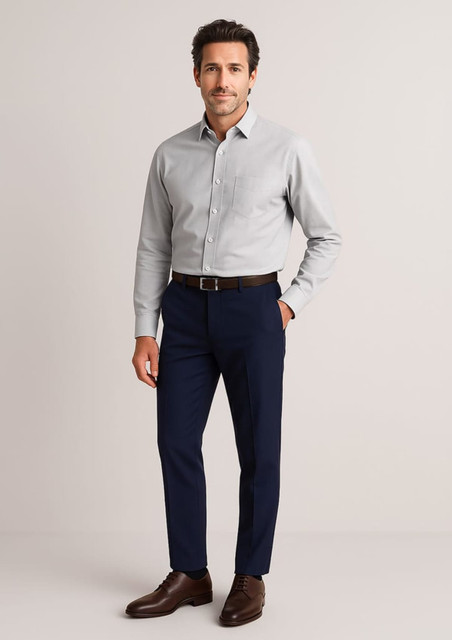A man wearing a light grey shirt and navy slim fit flat front pants, styled with brown shoes and a belt.