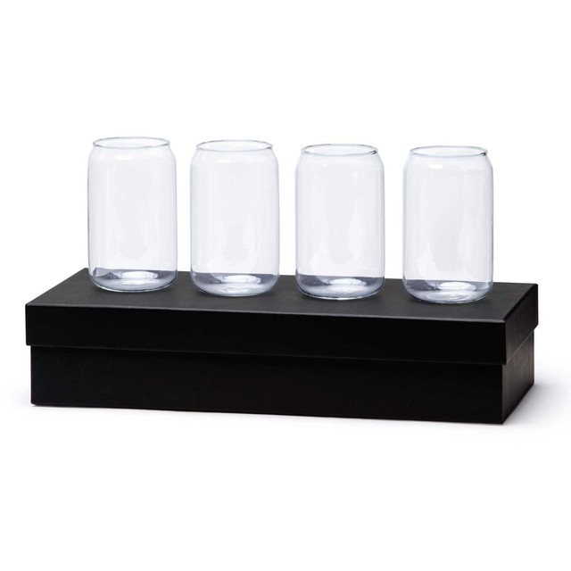 A set of four clear glass beer cans displayed on a black box. The glasses have a cylindrical shape. A set of four clear glass beer cans displayed on a black box. The glasses have a cylindrical shape.