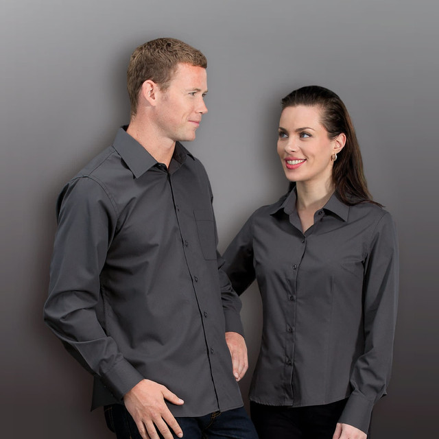 A grey button-up shirt for women, featuring a classic collar and a front pocket. The model displays a fitted style. A grey button-up shirt for women, featuring a classic collar and a front pocket. The model displays a fitted style.