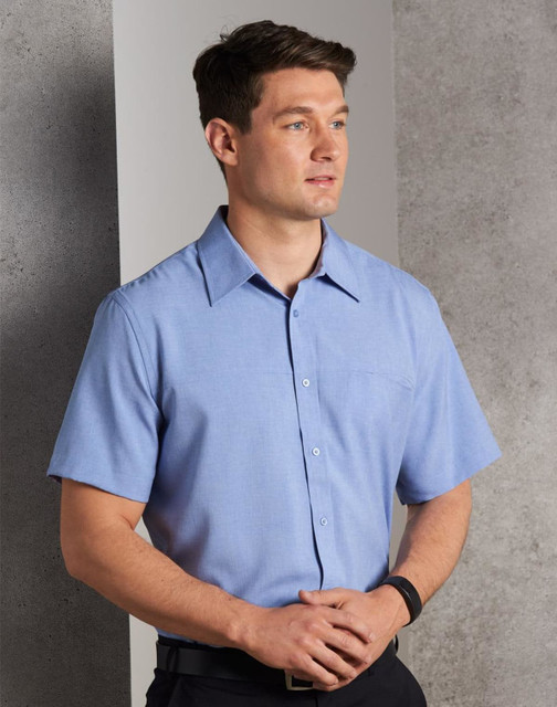 A short-sleeve men's shirt in light blue with a button-down front and a chest pocket, featuring a logo.