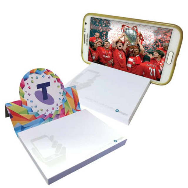 A white notepad with a colourful stand for holding a phone, displaying a cheerful celebration image.