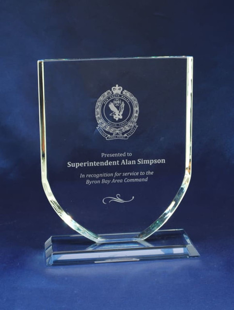 A glass plaque with a clear, angled design, featuring an emblem and engraved text on a blue background. A glass plaque with a clear, angled design, featuring an emblem and engraved text on a blue background.