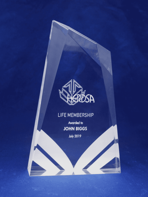 Acrylic trophy with a clear design, featuring angled edges and a logo, awarded for life membership.