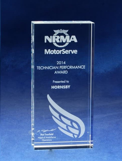 A clear optical crystal monolith trophy featuring etching, showcasing awards and a logo on a blue background.