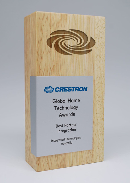 A wooden award with a printed metal plate, featuring a logo and text, set against a light grey background. A wooden award with a printed metal plate, featuring a logo and text, set against a light grey background.