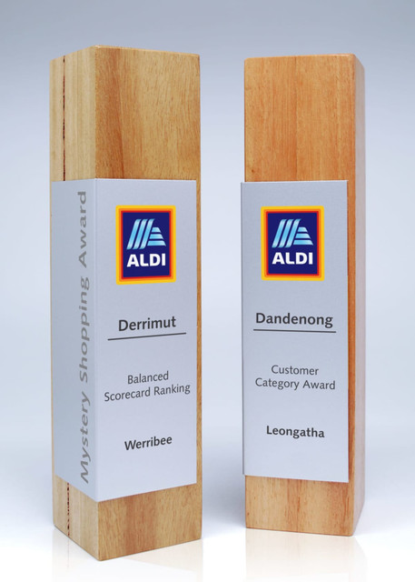Two wooden trophies with metal wraps, one in light wood and the other in a darker wood, featuring branding. Two wooden trophies with metal wraps, one in light wood and the other in a darker wood, featuring branding.