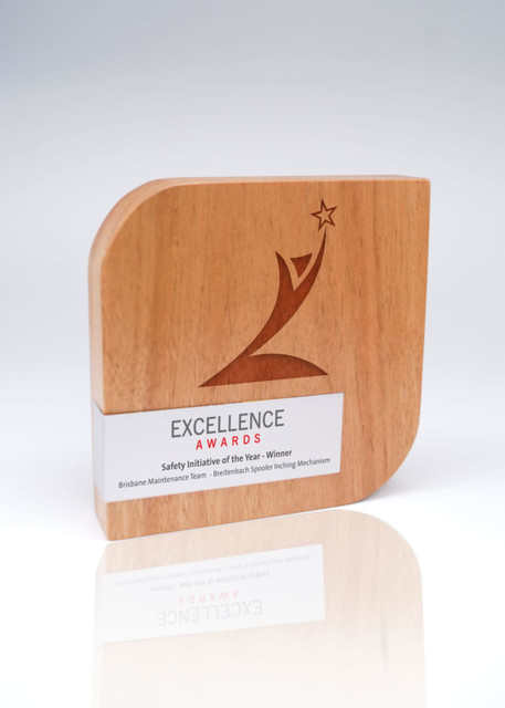 A wooden trophy featuring a stylised design and a metal wrap, showcasing an award for 'Excellence Awards'. A wooden trophy featuring a stylised design and a metal wrap, showcasing an award for 'Excellence Awards'.